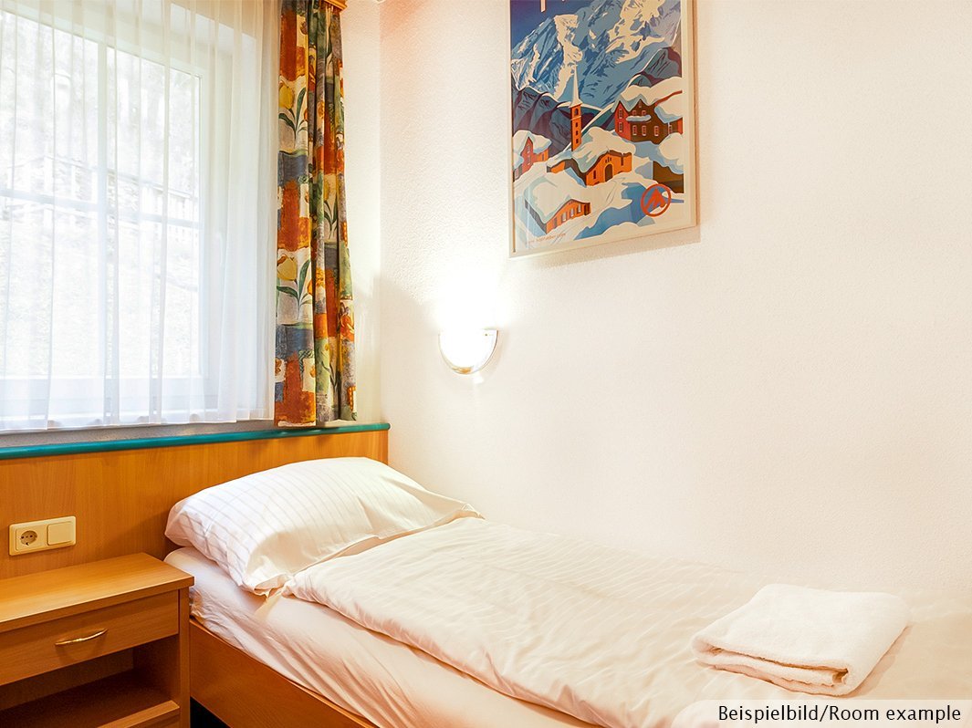 Das Bild zeigt Einzelbett mit Bettwäsche, Nachtschrank, Fenster, Steckdose, Lampe 