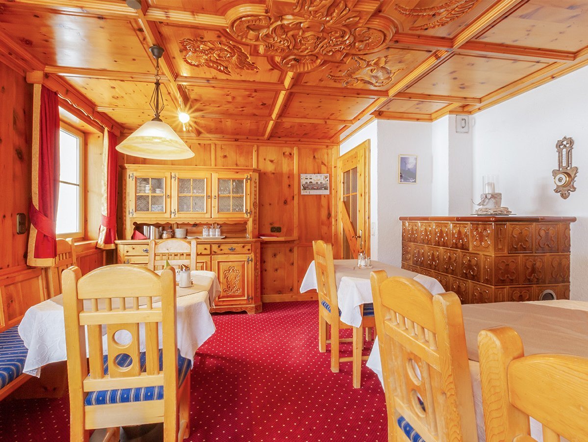 Das Bild zeigt den Frühstücksraum mit mehreren Tischen und Stühlen und einem Schrank