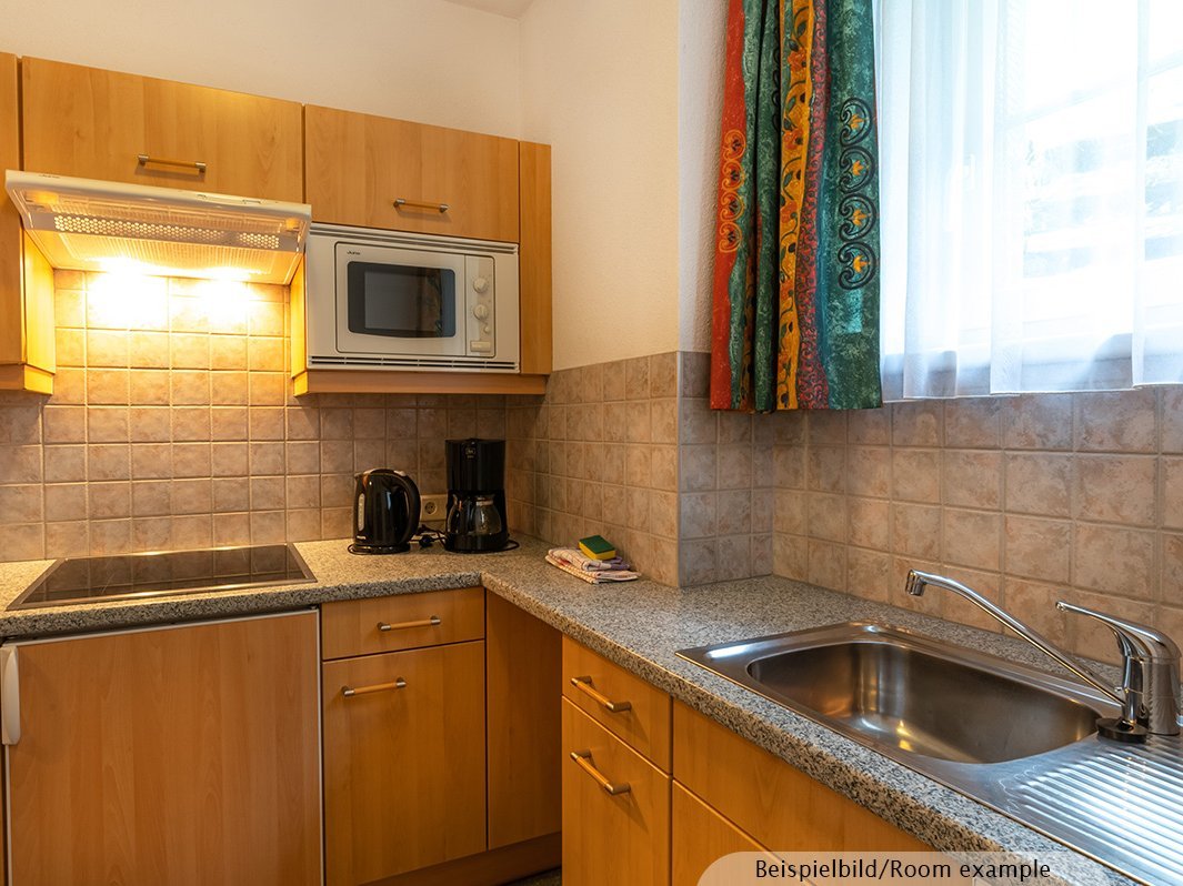 Das Bild zeigt Küchenzeile inklusive Wasserkocher, Kaffeemaschine, Spülmaschine, Mikrowelle, Arbeitsplatte, Kühlschrank, Herd, Dunstabzugshaube, Küchenschränke, Waschbecken, Spültücher, Fenster   