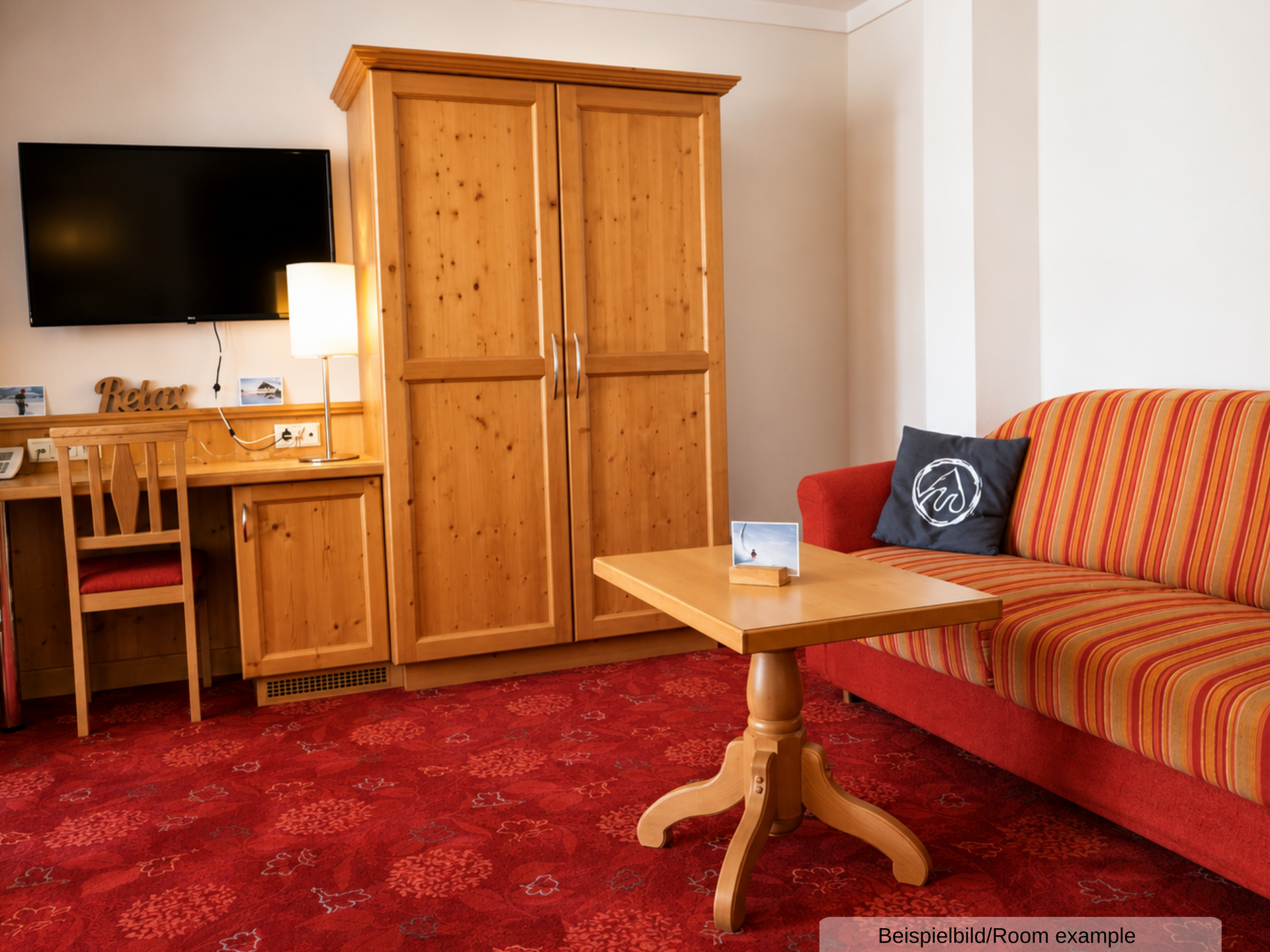 Beispielbild eines separaten Schlafzimmers in der Juniorsuite, mit Schlafsofa, Schrank, Sitzgelegenheit und TV
