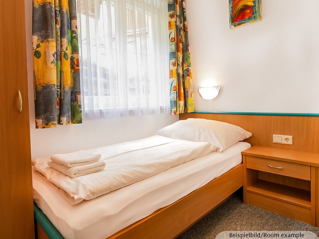 Das Bild zeigt Einzelbett mit Bettwäsche, Nachtschrank, Fenster, Schrank, Steckdose, Lampe 