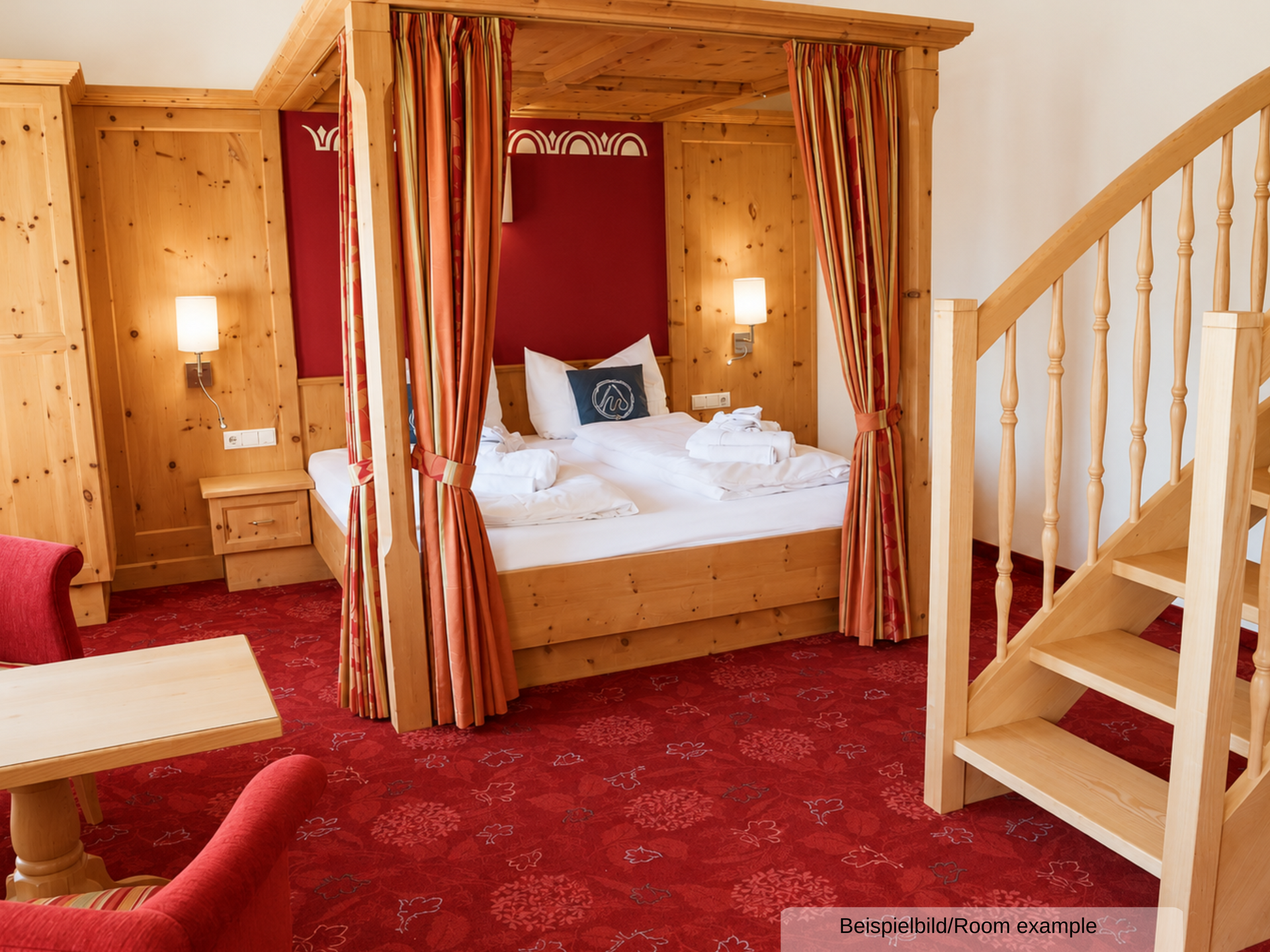 Beispielbild des Schlaf-/Wohnbereichs in der Juniorsuite, mit Doppelbett, Sitzgelegenheit und Treppenaufgang